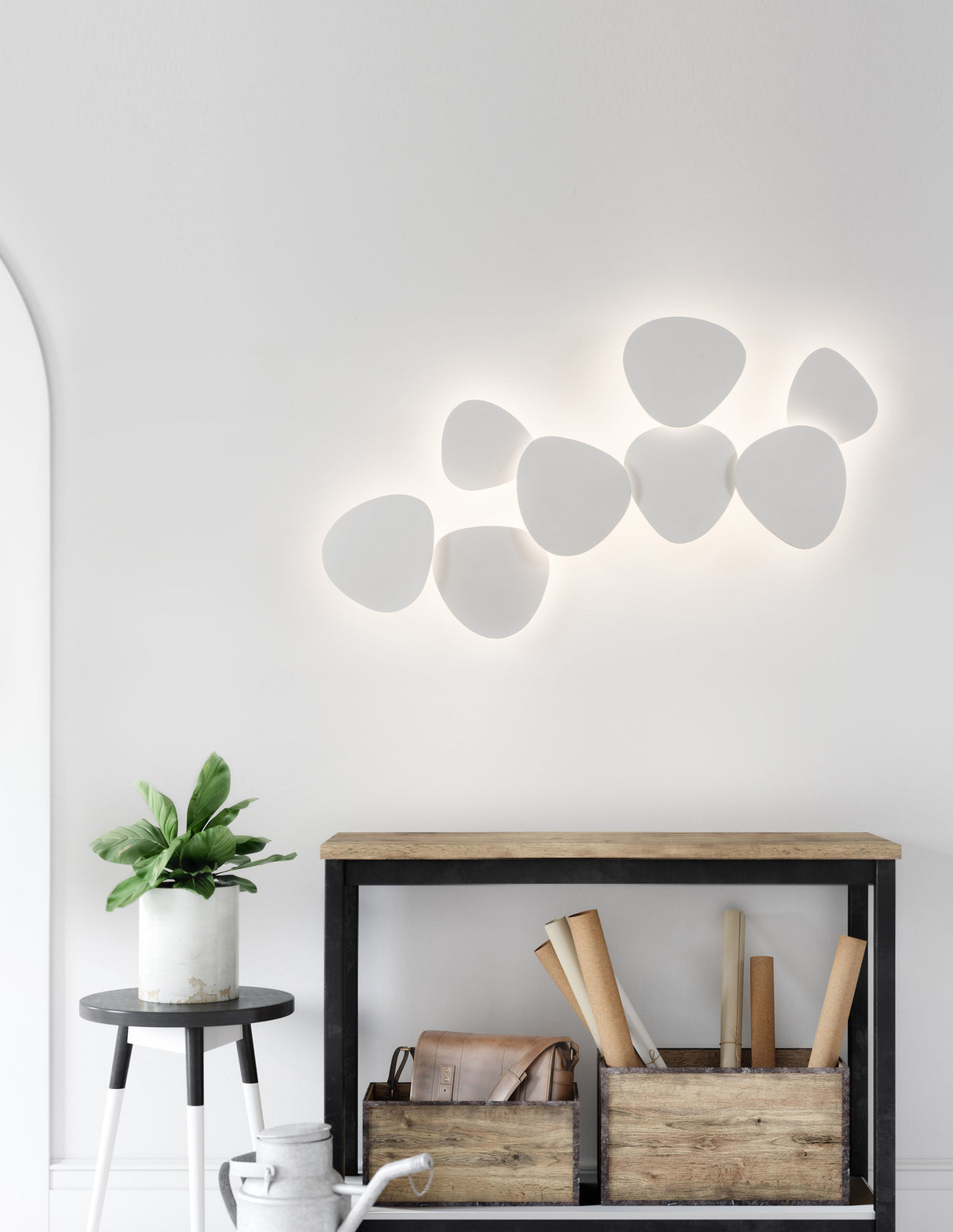 Moderne Wandleuchte mit sieben weißen, organisch geformten Lichtflächen an einer weißen Wand.