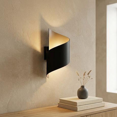 Moderne skulpturale Wandleuchte mit schwarzer geschwungener Metallschale und goldener Innenseite, leuchtend in einem minimalistischen Japandi-Interieur über Büchern und Vase.